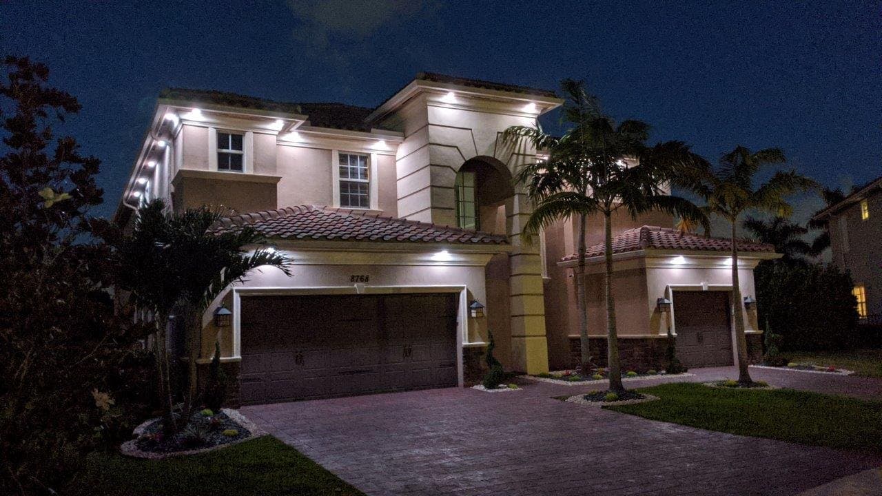 Warm white down lighting across a stucco home's arches.