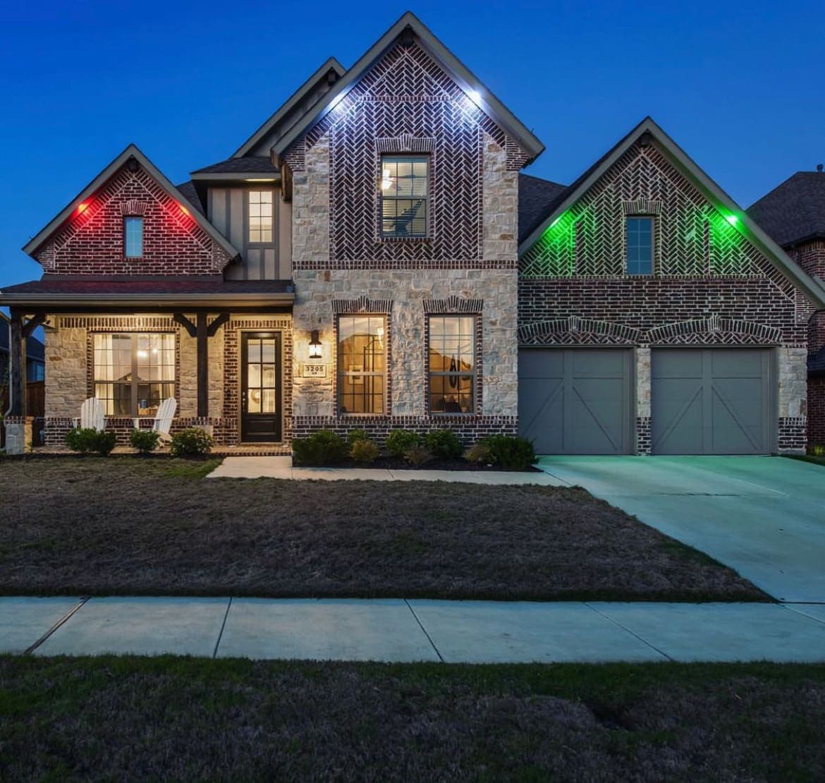 A brick home at dusk with warm down lighting and colored accents.