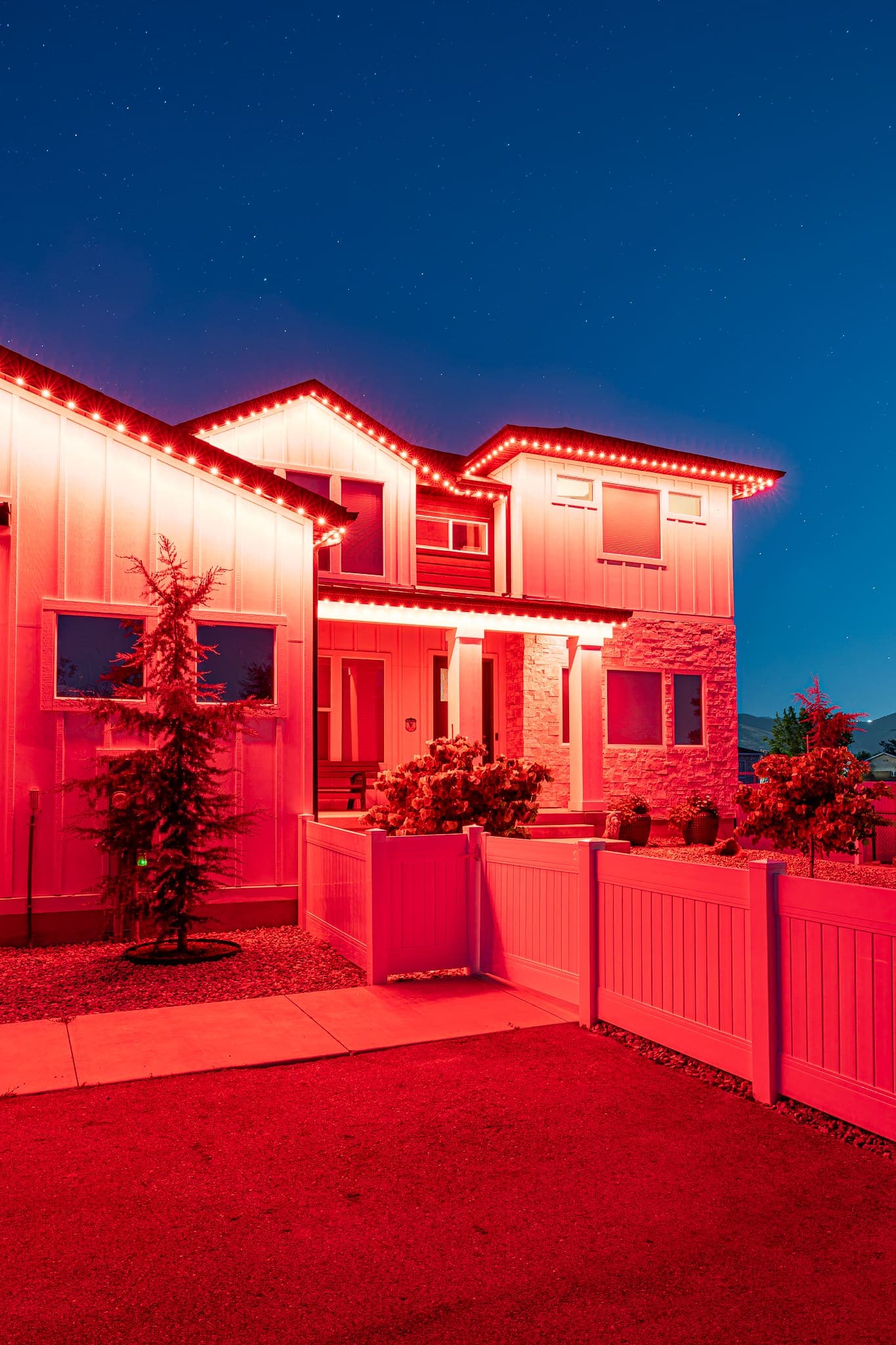 A two-story home glowing in bold red team colors.