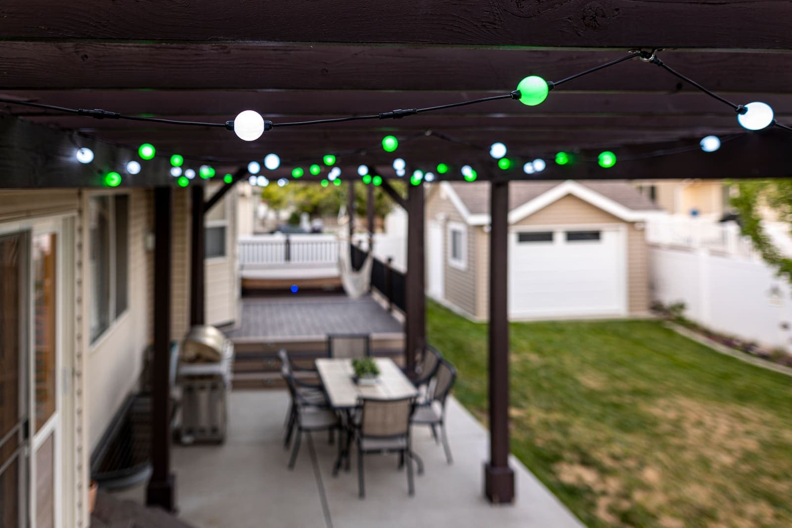 Globe lights in green over a backyard pergola.