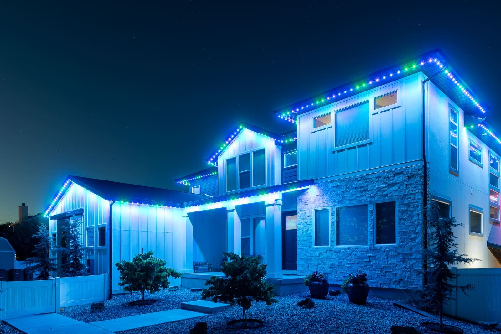 A farmhouse at dusk with its roofline traced in soft teal-white.