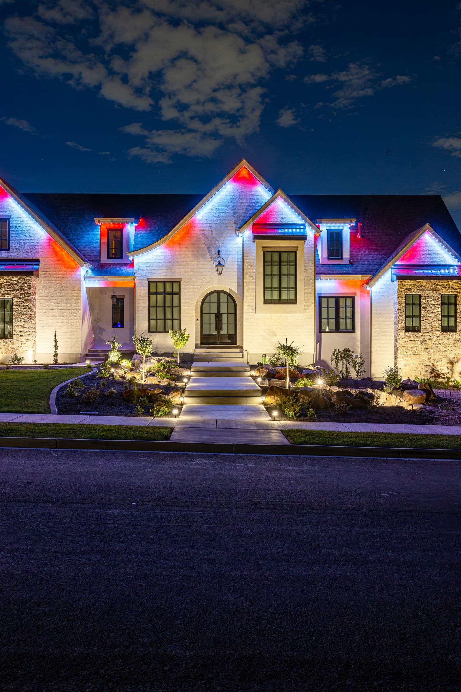 Colorful permanent lights tracing the roofline of a home at night.