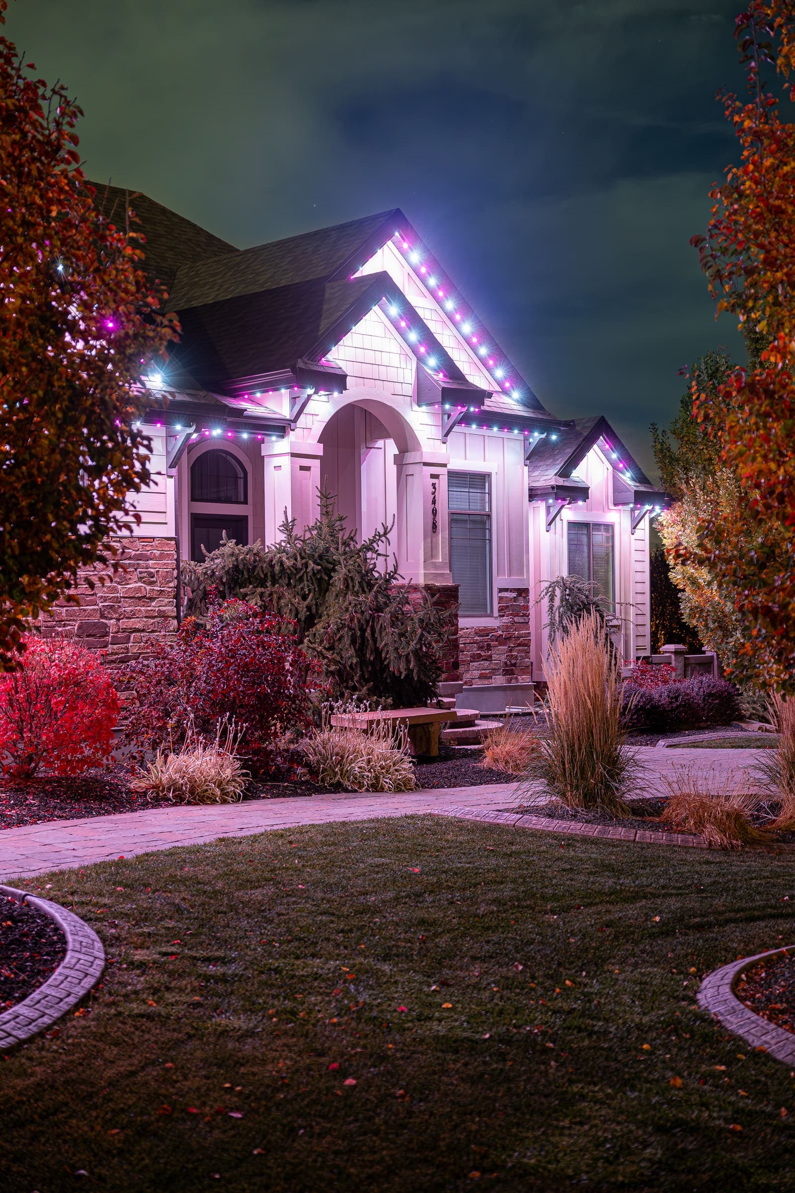 An entryway and garden beds washed in a soft colored glow.