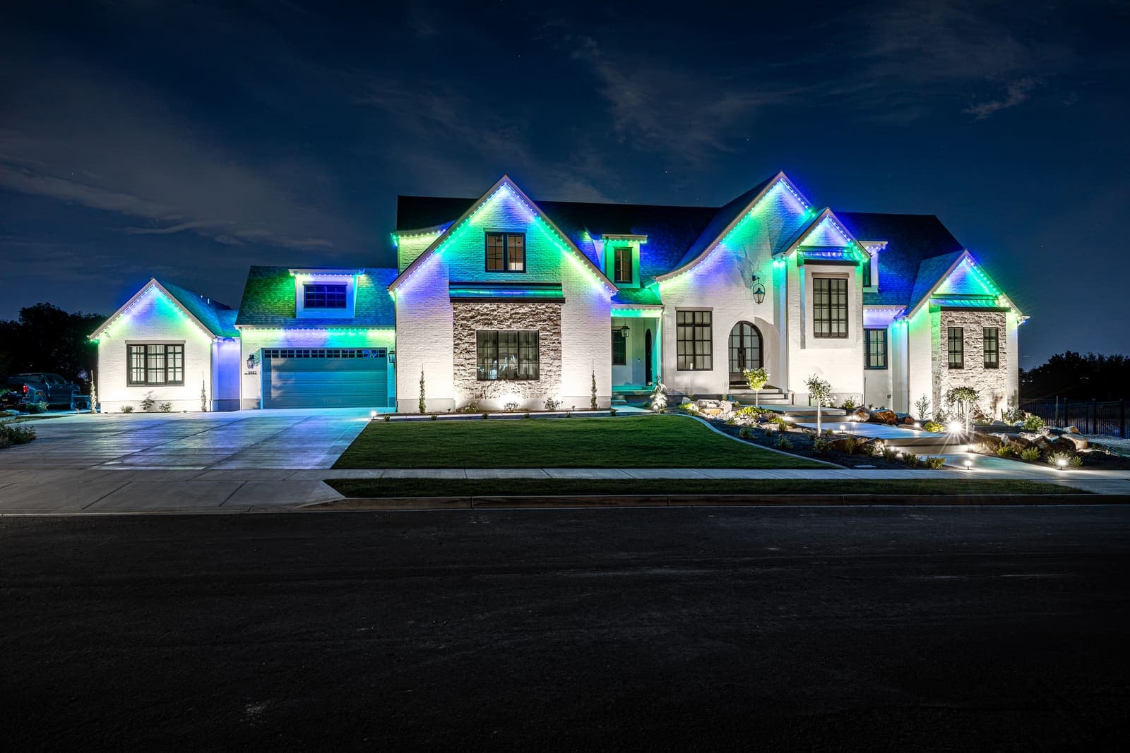 A modern farmhouse lit bright white on every face at night.